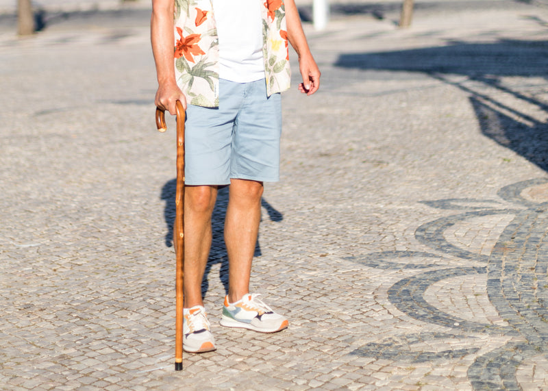 Person holding a cane on a paved walkway