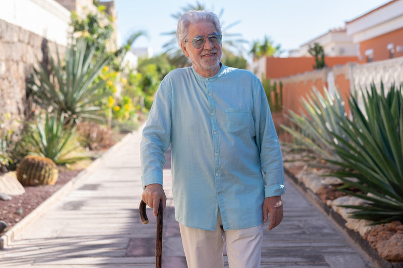 Man walking with a cane on a wooden path in a garden setting